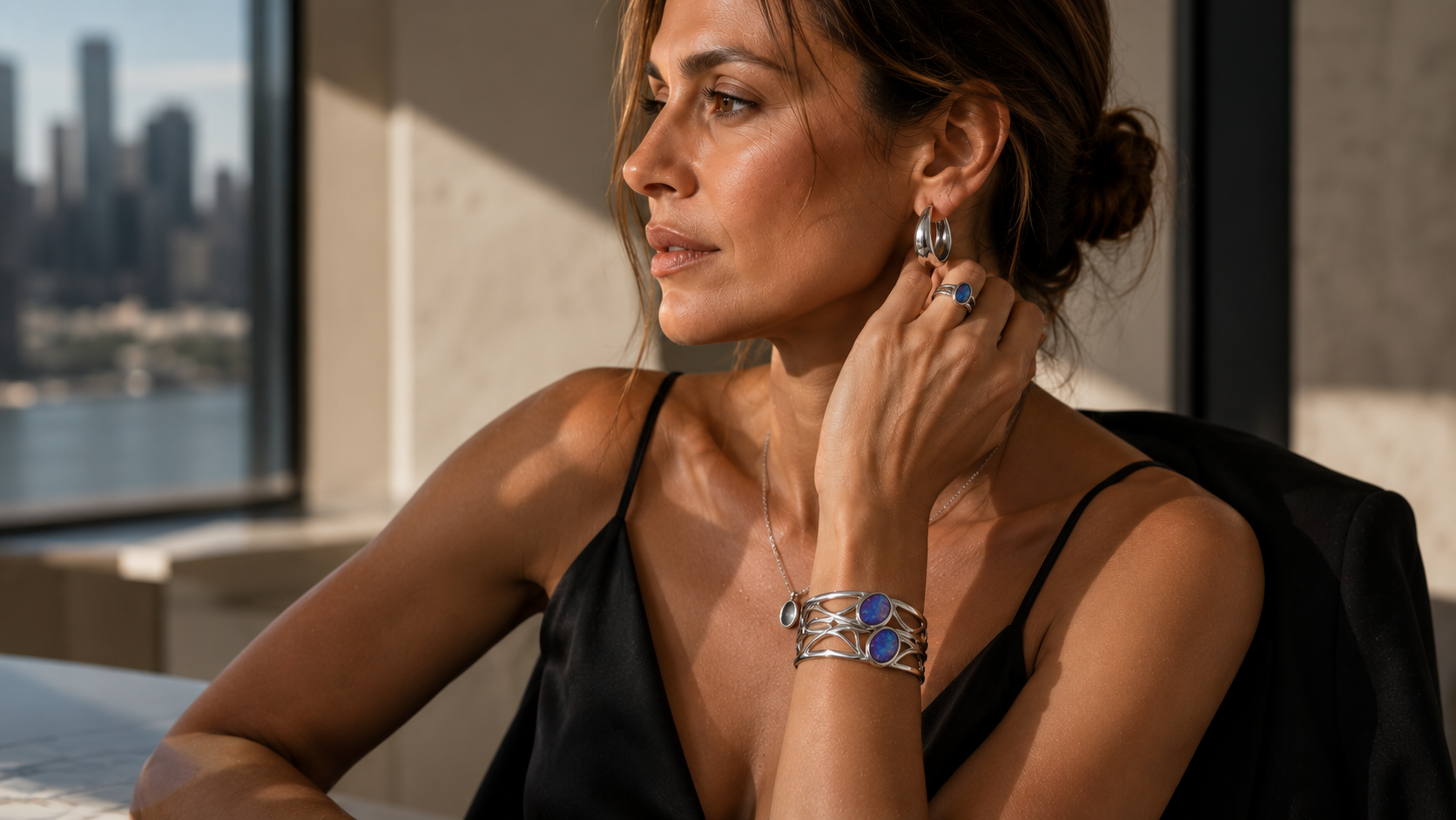 VY Jewelry sponsored campaign — model wearing the blue opal silver cuff, matching ring and silver hoops beside a city window